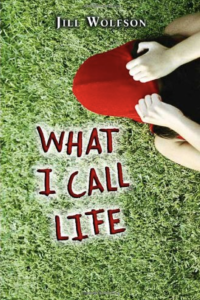 Young girl pulling her red hat over her face as she lays on the ground