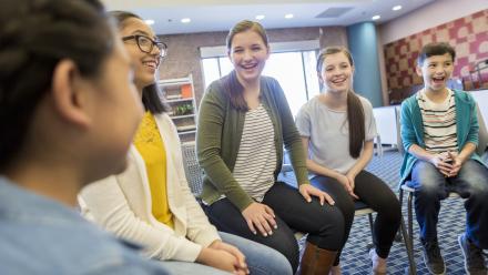Group of students smiling and talking to one another while seated