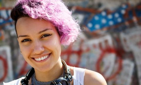 Multicultural high school girl with pink hair and headphones smiling