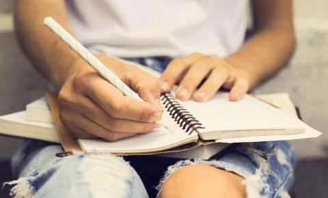 Close-up of high school student writing in spiral notebook